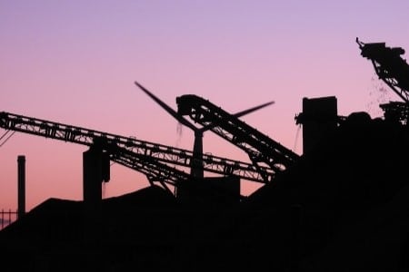 vue sur un couché de soleil sur un chantier avec un support de rouleaux pour convoyeur à bande